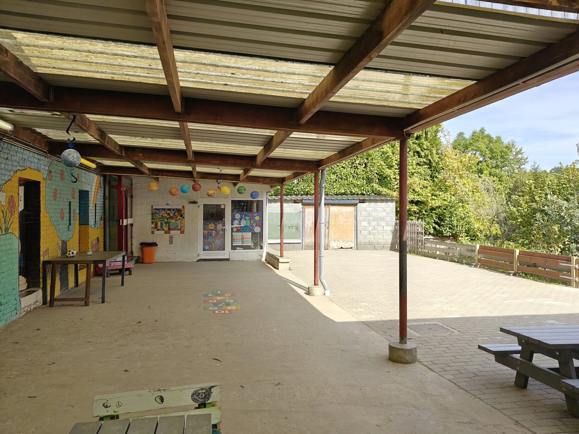 Le préau couvert, ses fresques murales et ses tables de pique-nique